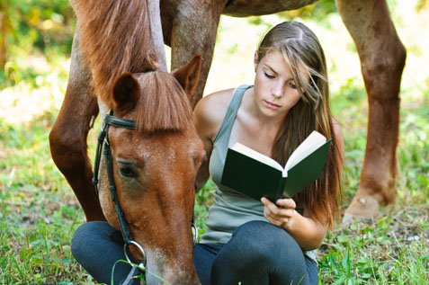 Girl reading book with horse